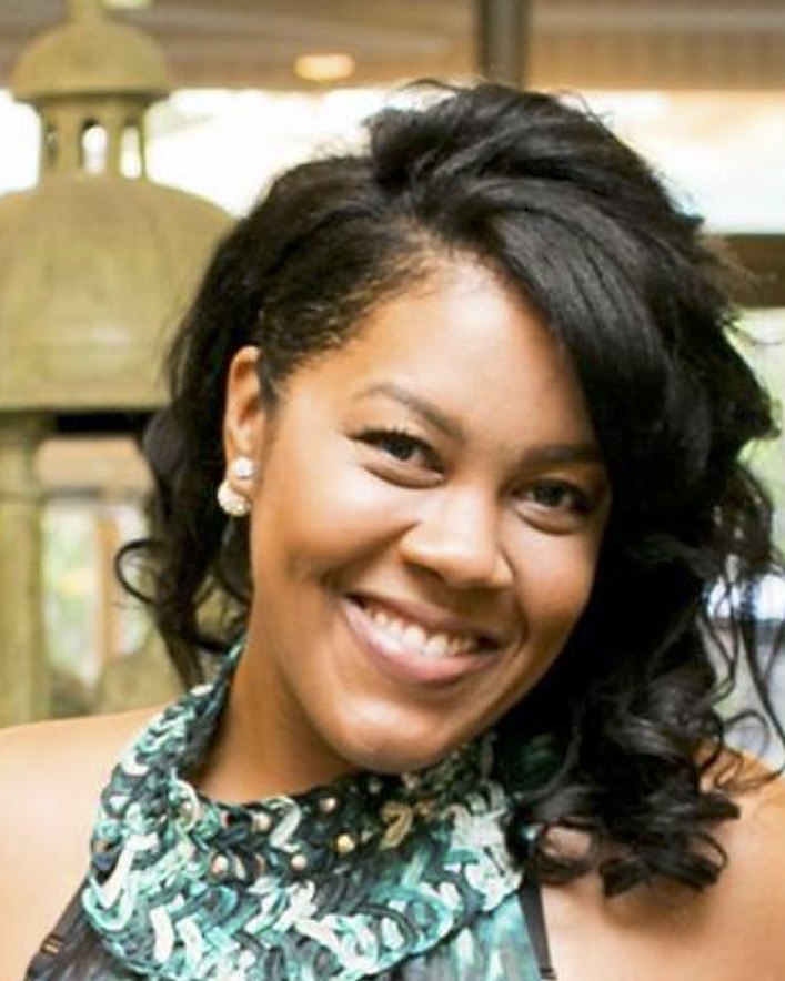 Candice Marie smiling, with dark curled hair and a green patterned scarf